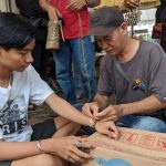 Erwin perajin simpai khas dayak kalimantan saat menganyamkan gelang dipergelangan tangan pengunjung Bazar UMKM Tanjung Bersinar (Kalimantanlive.com/ A Hidayat)