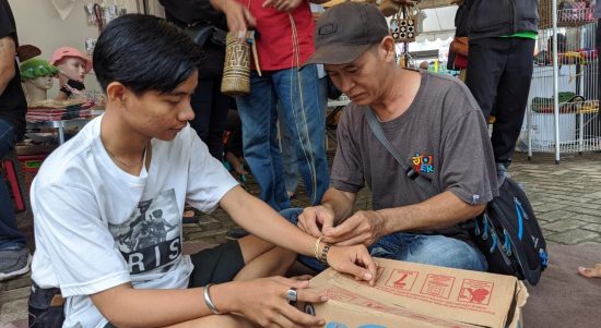 Erwin perajin simpai khas dayak kalimantan saat menganyamkan gelang dipergelangan tangan pengunjung Bazar UMKM Tanjung Bersinar (Kalimantanlive.com/ A Hidayat)