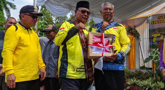 Paman Birin saat membagikan bantuan bendera merah putih kepada Kepala Sekolah SMAN 1 Tanjung, Wagiman. ` (Kalimantanlive.com/ A Hidayat)