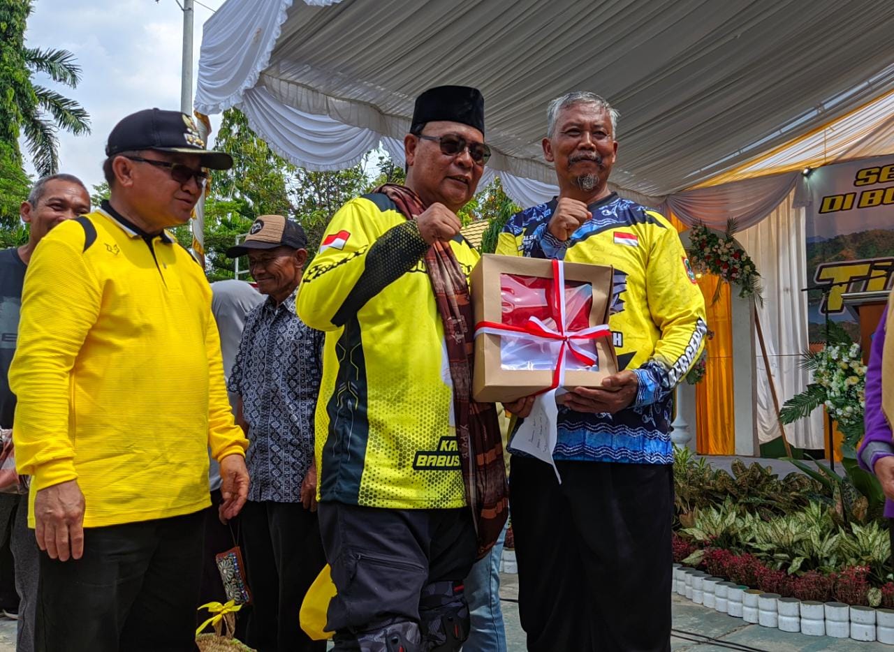 Paman Birin saat membagikan bantuan bendera merah putih kepada Kepala Sekolah SMAN 1 Tanjung, Wagiman. ` (Kalimantanlive.com/ A Hidayat)