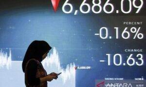 Pekerja berjalan di depan layar yang menampilkan pergerakan saham yang melemah di Bursa Efek Indonesia. (Antaranews)
