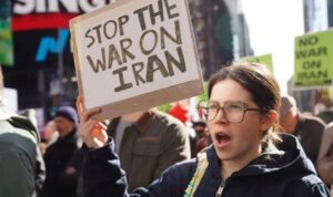 Warga membentangkan poster dan melakukan aksi unjuk rasa menentang serangan udara AS‑Israel terhadap Iran di Times Square, New York, Amerika Serikat, Sabtu (28/2/2026).